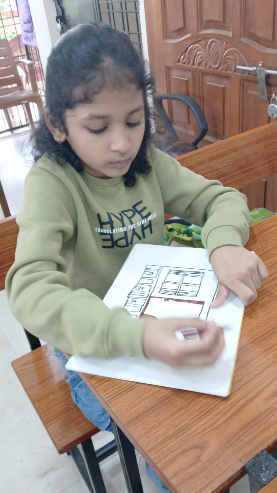 Student with glasses and crayons working on drawing at workshop